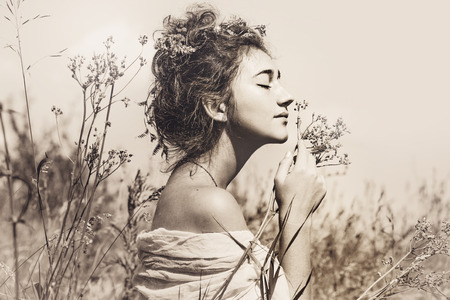 beautiful young woman with eyes closed on a field at sunsetの写真素材