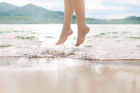 close up of a woman's legs jumping on the wave at the beachの写真素材