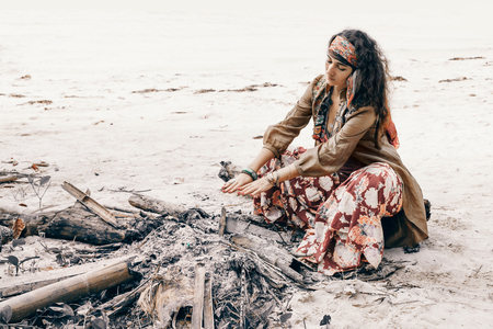 beautiful young gypsy style woman at fireの写真素材