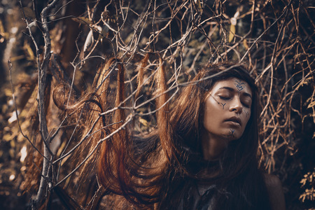 Beautiful young woman model with very long hair on branches. witch craftconceptの写真素材