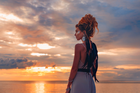 beautiful young woman in elegant dress on the beach at sunsetの写真素材