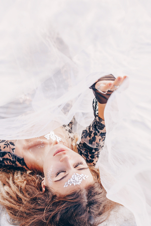 beautiful young fashionable woman lying on sand at sunsetの写真素材