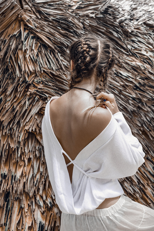 beautiful young fashionable woman in white dress on dry palm leaves backgroundの写真素材