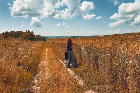 Cheerful young woman walking by the countryside road