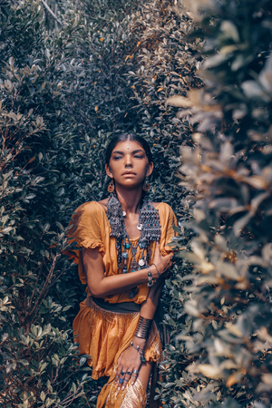 beautiful young fashionable woman with make up and stylish boho accessories posing on natural tropical backgroundの写真素材