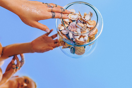 close up of woman hand reflection in mirror with sea shells