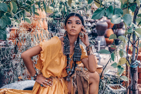 beautiful young fashionable woman with make up and stylish boho accessories posing on natural...