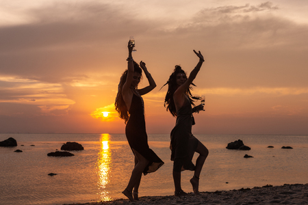 silhouette of beautiful young girls having fun on the beach at sunsetの写真素材
