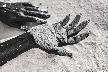 close up of woman hands painted black on sand. conceptual imageの写真素材