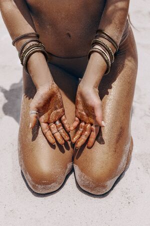 close up of beautiful young woman in bikini legs and arms with tanned skin on the beach