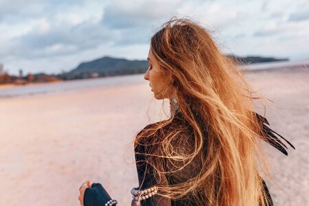 beautiful young tribal style woman on the beach at sunset