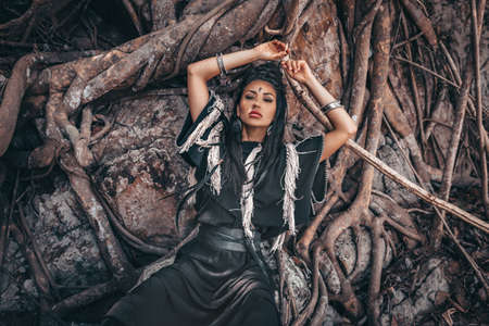 beautiful young stylish tribal woman at old tree roots background