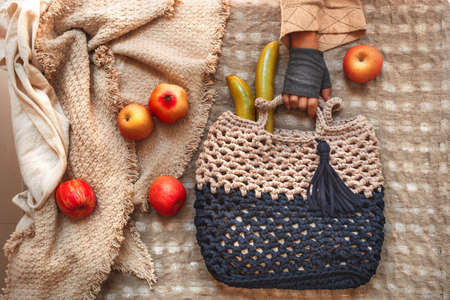 top view of stylish handmade bag with apples on a tableの写真素材
