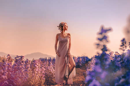 beautiful young stylish woman posing on the field at sunset