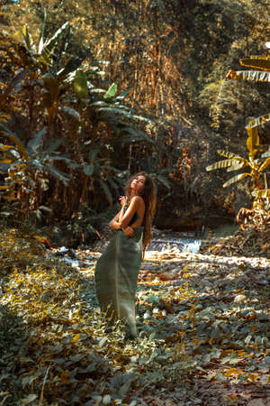 beautiful young sexy nude woman cover her body with palm leaf posing outdoors