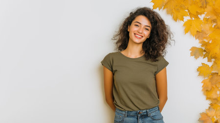 A photograph of a woman in her early thirties wearing jeans and an olive green T-shirt, with a soft smile and brown hair, and autumn leaves in the background. Generative AIの素材