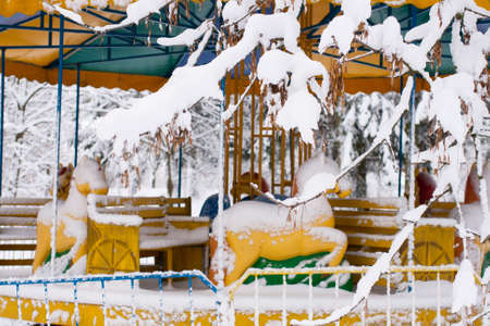 Amusement park. Empty carousel covered with snow. Horse in the snow.の写真素材