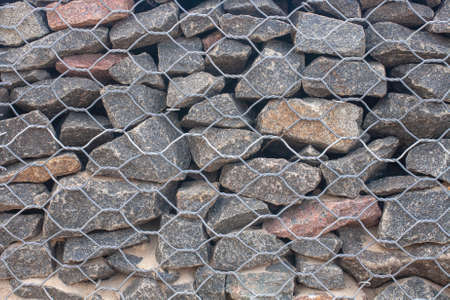 Texture of a gabion fence made of metal grating and large rough stoneの写真素材