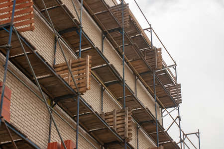 Scaffolding near the wall of the house. Construction of a 4-storey buildingの写真素材