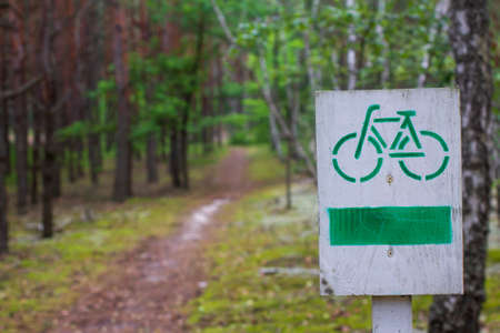 Cycle path in the forest. Bicycle path wooden sign.の写真素材