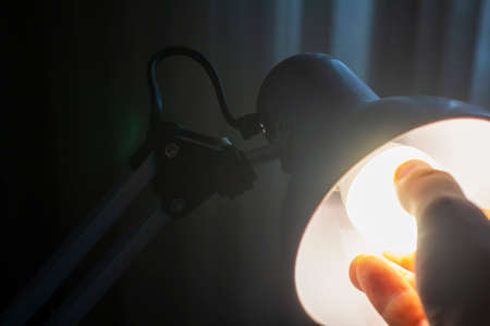 Changing of a light bulb. Removing bulb from the socket. Hand twists the light bulbの写真素材