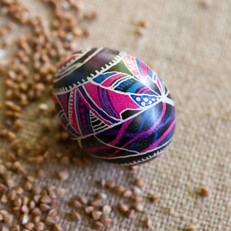 Easter egg with folklore ornament on canvas with buckwheat.