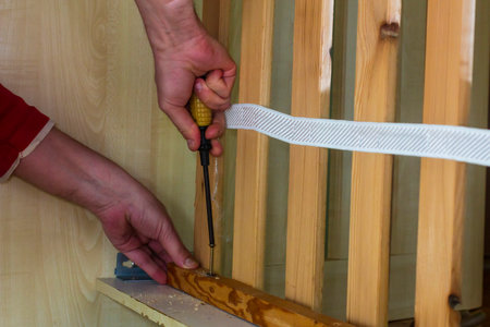 Driving a screw with a washer into wood with a screwdriverの写真素材