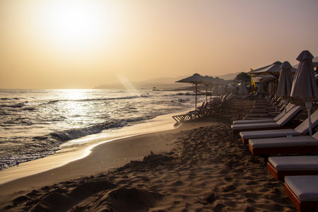 Mediterranean beach with sun loungers on Crete in Greece at sunriseの写真素材