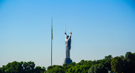 A monumental statue in Kyiv called Motherland and a flagpole with the Ukrainian flagの写真素材