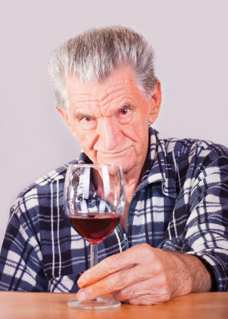 A portrait of an elderly man with a glass of red wine.の写真素材