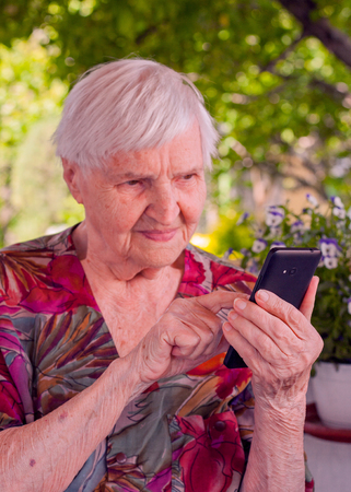 Smiling elderly woman dialing phone number one of her relative.の写真素材