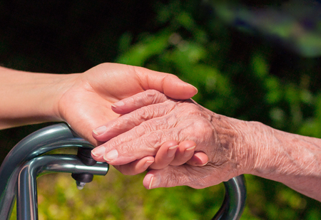 Lady holding an elderly woman's hand with walker.の写真素材