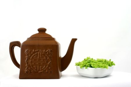 Small square brown teapot witch chinese pattern opposite to green flowers put in white porcelainの写真素材