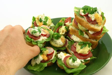 Hand picking a tasty sandwich from a plate