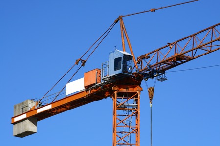 close up view at the top of orange tower crane with blue cabinの写真素材