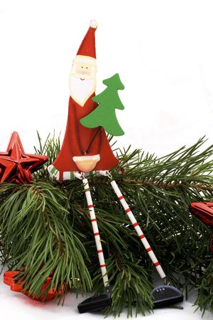 Wooden santa claus sitting on a pine branch on a whiteの写真素材
