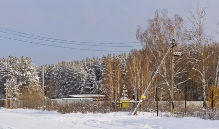 Country house behind a fence surrounded by trees in the snowの写真素材