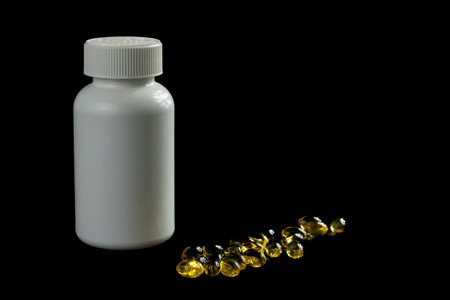 <p>Omega 3 capsules in a white plastic bottle on a black background</p>の写真素材