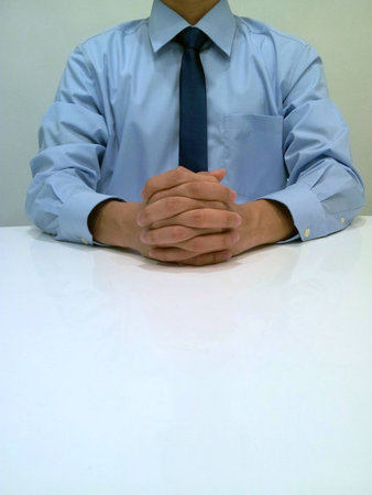 Businessman sitting with hands on desk.の素材