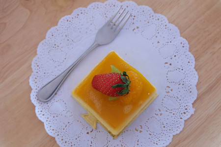 Orange cake with strawberry on wooden plate.の写真素材