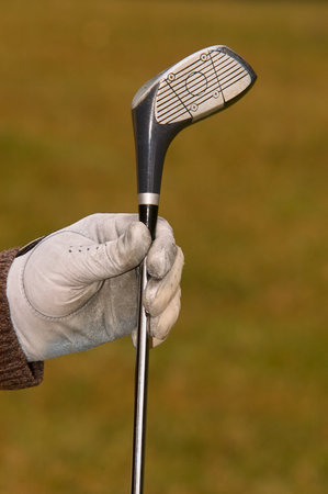 Gloved hand holding golf clubの写真素材