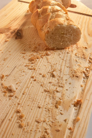 Bread slices on a wooden board with crumbs aroundの写真素材