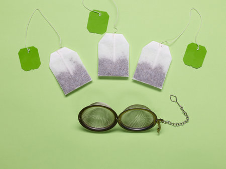 Three green tea bags and metal tea filter on green backgroundの写真素材