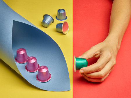Colorful still life of coffee capsules and hand picking up a capsuleの写真素材