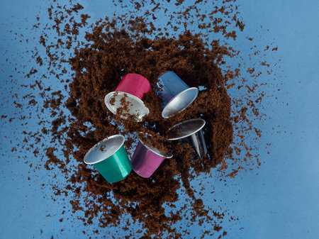 Coffee capsules among coffee powder explosionの写真素材
