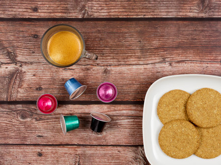 Coffee capsules, next to cup of coffee and plate with cookiesの写真素材