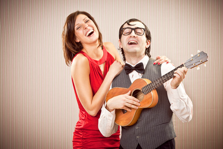 nerd boyfriend man in love with beautiful woman play a serenade song with ukulele for Valentine Dayの写真素材