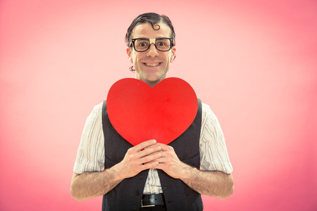 Nerd man with glasses happy for love heart on pink for valentine dayの写真素材