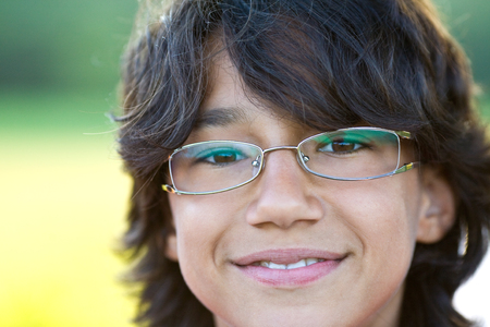young happy boy with long hair and glasses outdoor portraitの写真素材