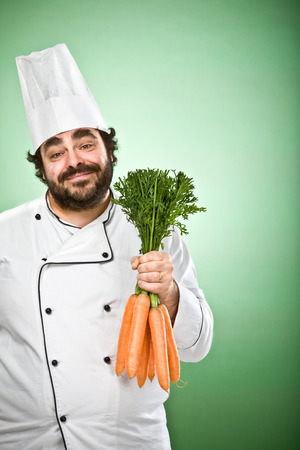 happy relaxed chef holding carrots isolated on greenの写真素材